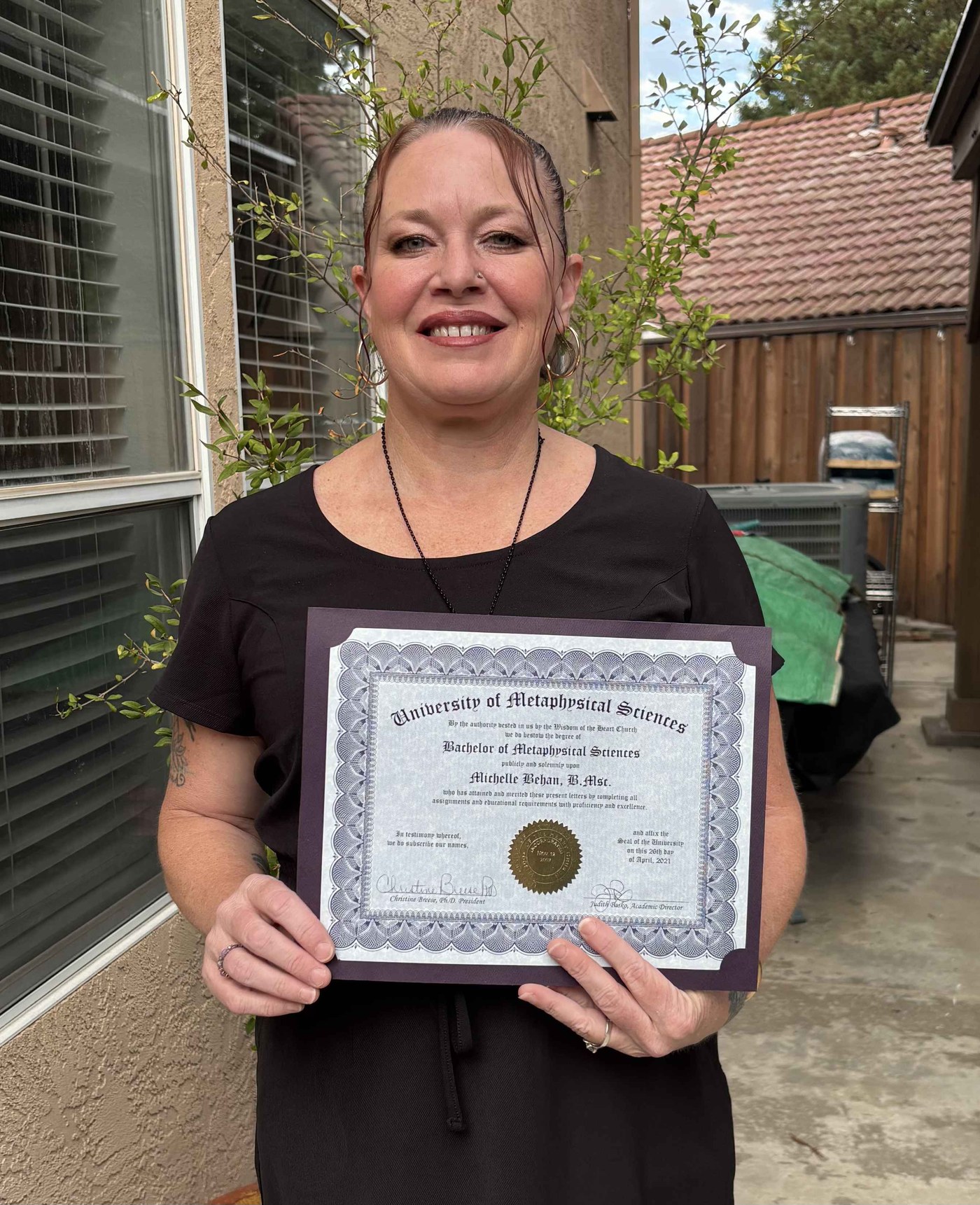 Michelle holding her Bachelor of Metaphysical Sciences diploma
